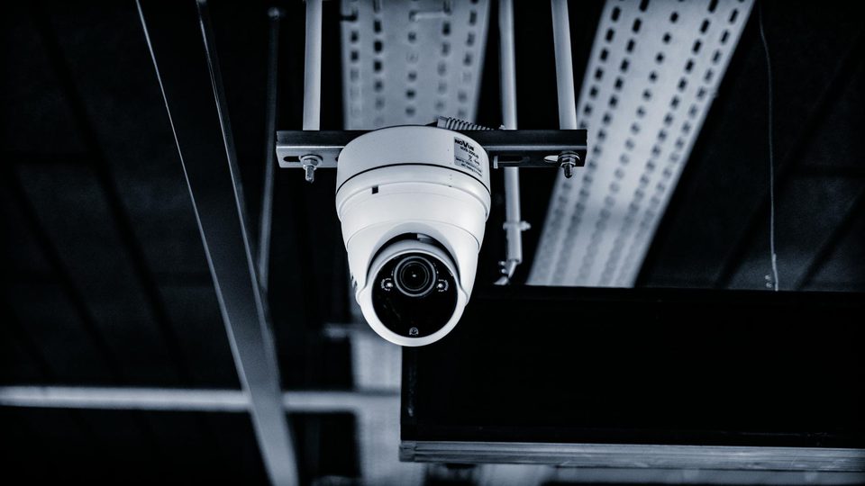 A white CCTV camera used as a lead visual for an article about DRI criteria and EO/IR system selection.
