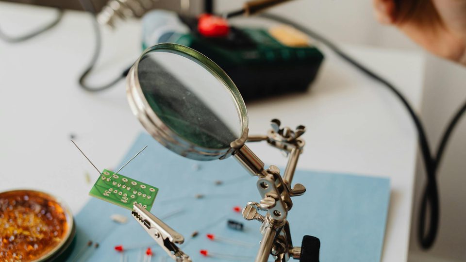 A small circuit board viewed under a magnifying glass.