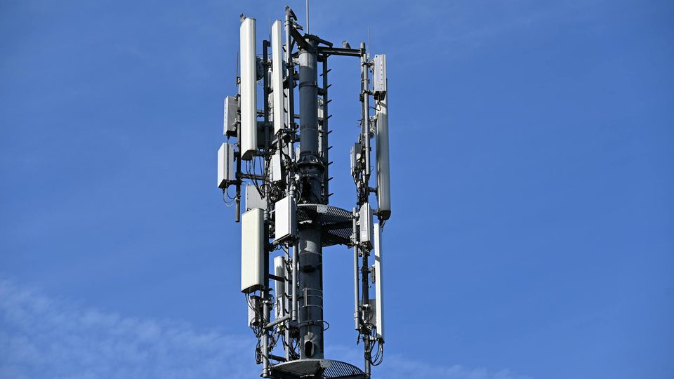 A cell tower rising against a clear blue sky.
