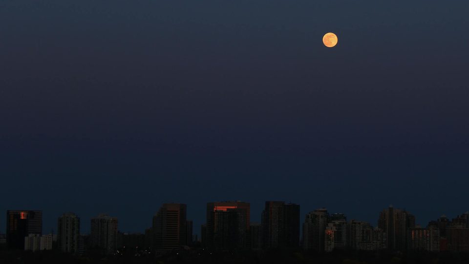 Full moon over a city skyline for a National Day and Mid-Autumn holiday notice.